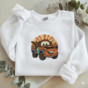 May include: A white ceramic mug with a black handle and the text "But First, Coffee" in a bold, black font. The mug is set against a neutral background, highlighting its simple design.