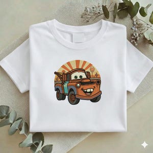 May include: A white ceramic mug with a black handle and the text "But First, Coffee" in a black, handwritten-style font. The mug is on a white surface.