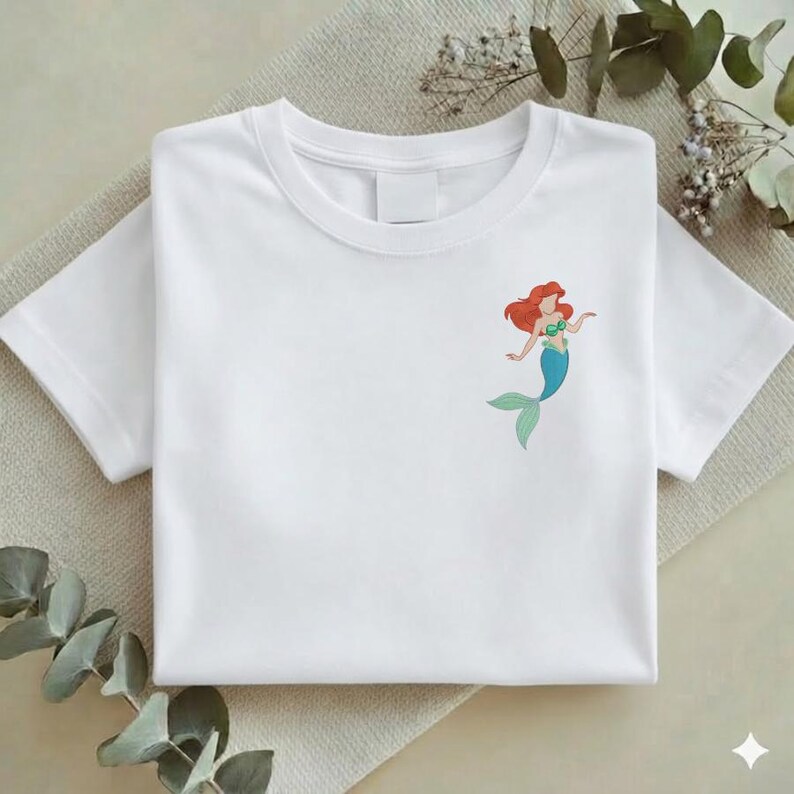 May include: A white ceramic mug with a black handle and the text "But First, Coffee" in a bold, black font. The mug is set against a blurred background, suggesting a cozy setting.