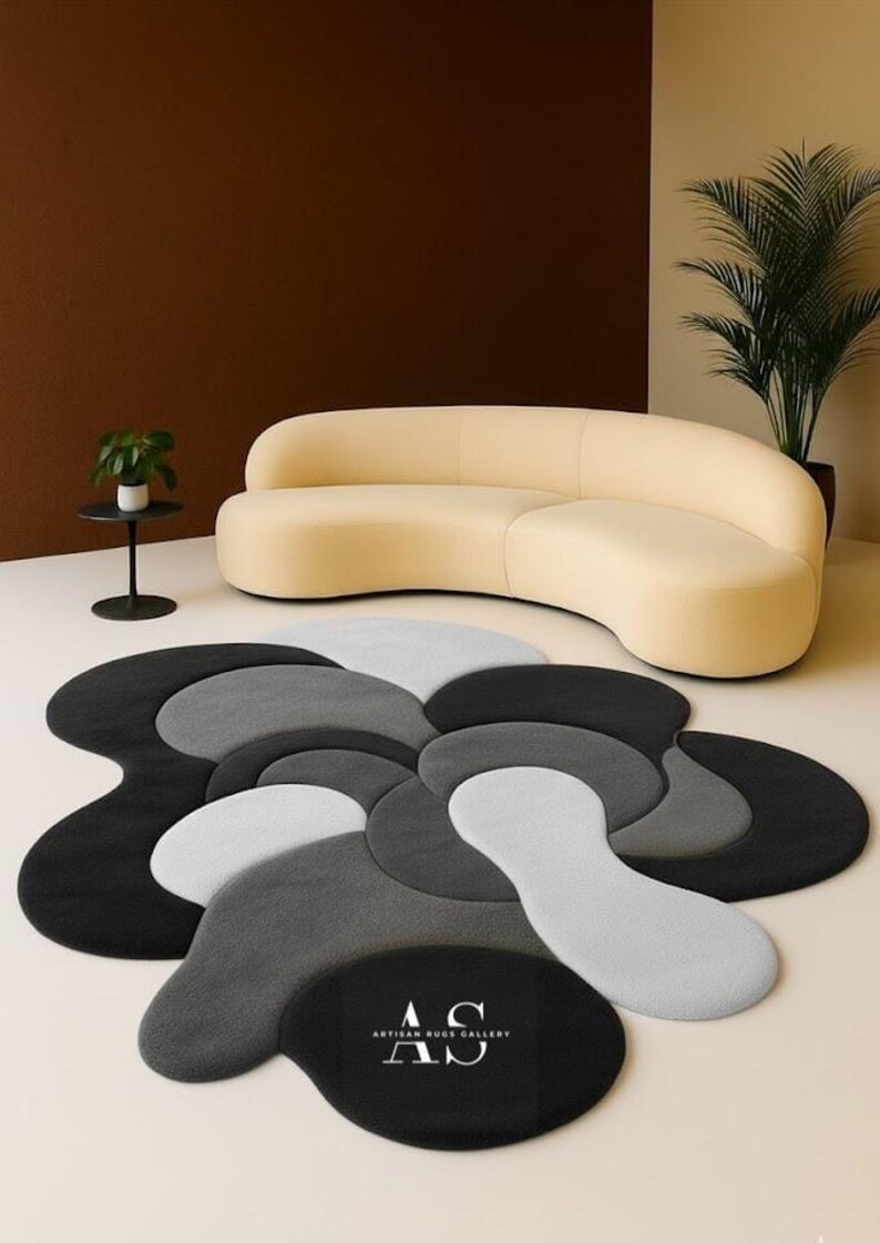 Puede incluir: Una alfombra moderna con un dise&ntilde;o abstracto &uacute;nico en tonos grises, negros y blancos. La alfombra presenta un patr&oacute;n floral con formas superpuestas. Las palabras "ARTISAN RUG GALLERY" est&aacute;n impresas en la alfombra.
