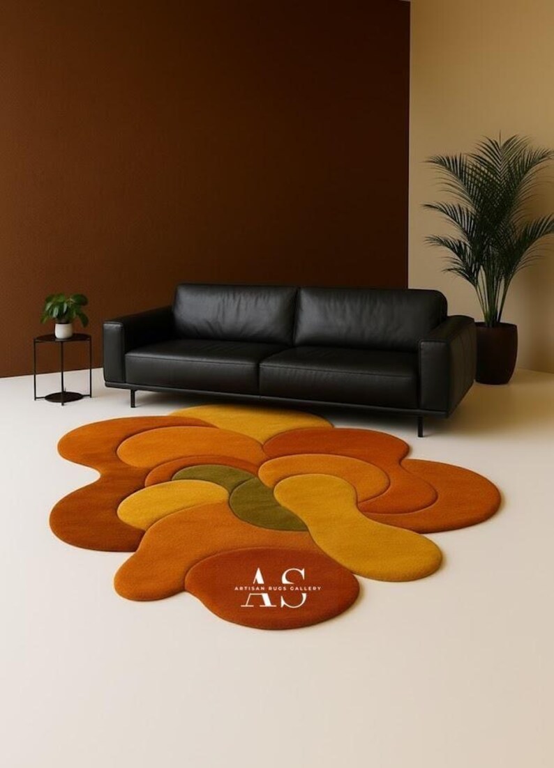 Puede incluir: Un sal&oacute;n moderno con un sof&aacute; de cuero negro y una alfombra abstracta y colorida. La alfombra tiene un dise&ntilde;o floral con tonos de naranja, amarillo y verde. La alfombra tiene el texto "AS ARTISAN RUGS GALLERY".