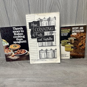 May include: Three vintage cookbooks are displayed. The titles include "There's more to Italian cooking than spaghetti", "Home Canning of Fruits and Vegetables", and "Presto Recipe and Instruction Book". The books are in various sizes and colors.