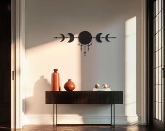 Puede incluir: Arte de pared de metal negro con diseño de fases lunares y elementos decorativos colgantes. Debajo, una consola de madera oscura con dos jarrones naranjas y dos pequeños objetos esféricos. La mesa mide 120 cm de largo.