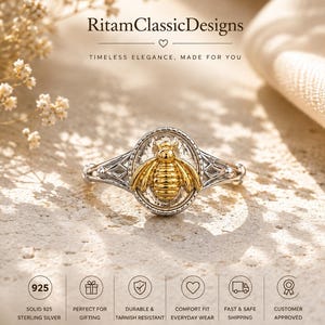 May include: A silver ring featuring a central oval plaque with a raised gold-toned bee motif. The band has intricate geometric cutouts on the sides. The text RitamClassicDesigns is visible above the ring, with various icons and labels below.