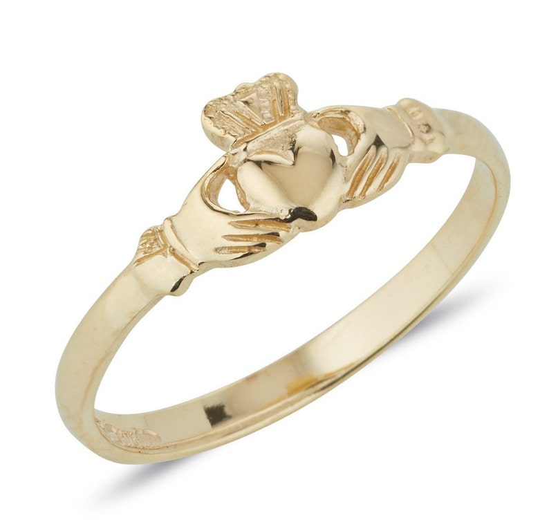 Dainty Gold Irish made Claddagh ring. In the centre of the ring is two gently cupped hands holding a heart, with an intricate crown resting above the heart. Ring has a polished, shiny finish.