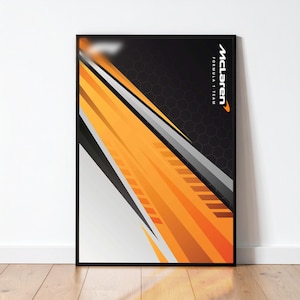 Puede incluir: Un póster enmarcado con un diseño abstracto dinámico en naranja, negro, blanco y gris. El logotipo de McLaren Formula 1 Team es visible en la esquina superior derecha. El arte tiene un estilo moderno y geométrico.