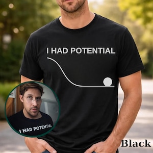 May include: Black t-shirt with the white text "I HAD POTENTIAL" above a graphic of a ball rolling down a slope. A smaller image of a person wearing a similar shirt is in the lower left corner. The word "Black" is at the bottom right.
