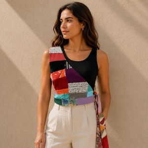 Könnte beinhalten: Ein ärmelloses, schwarzes Ripp-Top mit einem mehrfarbigen Patchwork-Einsatz auf der Vorderseite. Der Einsatz besteht aus verschiedenen Stoffquadraten in Rot, Lila, Blau und Weiß mit schwarzem Schrifttext. Ein langes, gemustertes Stoffband hängt seitlich herab.