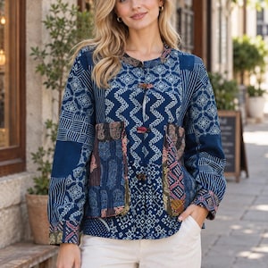 Può includere: Una giacca a maniche lunghe caratterizzata da un design patchwork nei toni del blu, bianco e con accenti multicolori. Il capo presenta uno scollo rotondo, una chiusura frontale con bottoni a levetta e due tasche anteriori con motivi complessi.