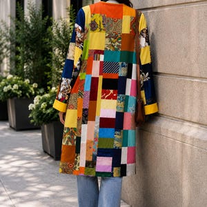 May include: A long-sleeved coat featuring a vibrant patchwork design composed of various rectangular fabric swatches in colors including orange, yellow, blue, pink, and green, paired with light blue denim jeans and a brown shoulder bag.