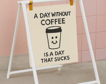May include: White A-frame sign with the text "A DAY WITHOUT COFFEE IS A DAY THAT SUCKS" and a coffee cup graphic. The sign is held together with yellow fasteners. The background is a pink tiled wall.
