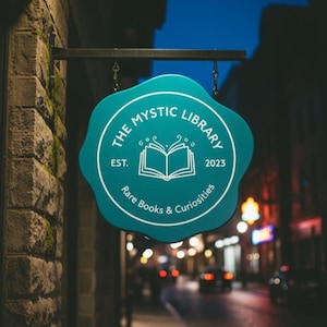 Peut inclure: Un panneau turquoise pour "The Mystic Library" est suspendu &agrave; un b&acirc;timent en briques. Le panneau a une forme unique avec du texte blanc et un dessin de livre ouvert. Le panneau indique "Rare Books & Curiosities" et "Est. 2023".