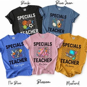 May include: Five short-sleeved t-shirts in black, blue jean, flo blue, blossom, and mustard colors. Each shirt features the text "SPECIALS TEACHER" with repeating "SPECIALS" text in the background and unique graphics including sports balls, musical instruments, science equipment, art supplies, and a laptop.