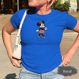 May include: A white ceramic mug with a black handle and the text "But First, Coffee" in a bold, black font. The mug is set against a blurred background, suggesting a cozy setting.