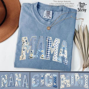 May include: A light blue Comfort Colors t-shirt with the word "MAMA" appliqued on the front in a patchwork design. The patchwork includes floral, gingham, and polka dot patterns in shades of blue and white. A gold necklace is draped on the shirt.
