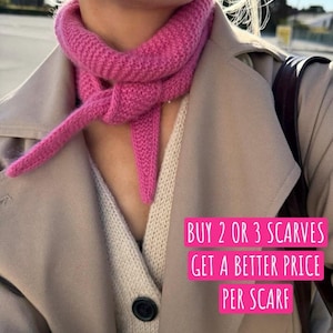 Op de afbeelding: Een felroze gebreide sjaal geknoopt rond de nek, gedragen over een beige vest en een beige trenchcoat. De afbeelding bevat de tekst: BUY 2 OR 3 SCARVES GET A BETTER PRICE PER SCARF. De sjaal heeft een getextureerd patroon in ribbelsteek.
