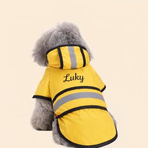 May include: A yellow dog raincoat with black trim and reflective stripes. The word "Luky" is embroidered on the back. The raincoat has a hood and is designed to fit a dog.