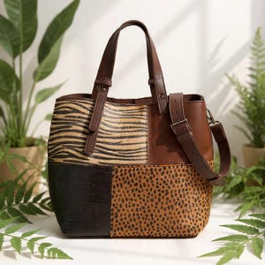 Puede incluir: Un bolso tote patchwork con una variedad de estampados de animales. El bolso presenta texturas de cebra, leopardo y cocodrilo en tonos marrón, beige y negro. Tiene asas de cuero marrón y una correa de hombro desmontable.