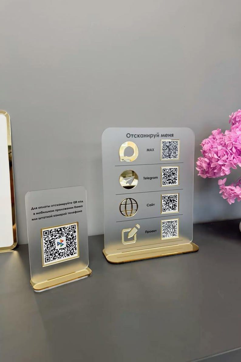 Op de afbeelding: Twee rechthoekige borden van mat acryl met gouden voetstukken. Het linkerbord bevat een QR-code en Russische tekst. Het rechterbord toont vier rijen met gouden iconen, de tekst MAX, Telegram, Sait, Proekt en vier verschillende QR-codes.