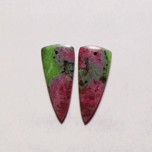 May include: Two triangular-shaped pendants made of zoisite stone featuring a mottled pattern of vibrant magenta and lime green colors with dark inclusions. Each piece has a small, circular hole drilled near the top edge for suspension.