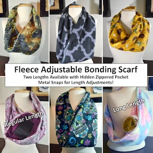 May include: A collection of fleece adjustable bonding scarves featuring various patterns including camouflage, grey lattice, sunflowers, paisley, sugar skulls, and a pastel tie-dye print. Each scarf includes a hidden zippered pocket and metal snaps.