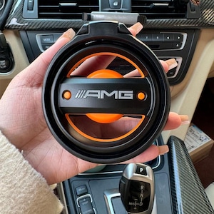 Op de afbeelding: Een witte keramische mok met een zwart handvat en de tekst "But First, Coffee" in een zwarte, handgeschreven lettertype. De mok staat op een wit oppervlak.