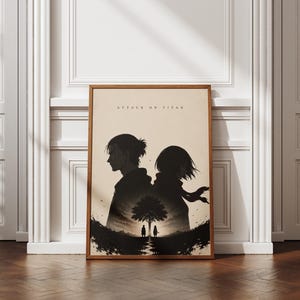 May include: A rectangular framed wall art print featuring a beige background with the text ATTACK ON TITAN at the top. The graphic displays two dark silhouettes of characters standing back-to-back above a small tree and two tiny figures.