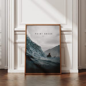 May include: A rectangular framed poster featuring a dark ocean wave and a surfer. The text reads POINT BREAK 1991 at the top and IT'S NOT ABOUT THE WAVES IT'S ABOUT THE LIFE at the bottom. The frame is brown wood with a thin profile.