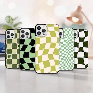 May include: A collection of five phone cases with various checkerboard patterns in green, black, and cream colors. One case features a four-leaf clover design. The cases are displayed upright, showcasing their unique designs.