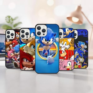 Puede incluir: Una colección de fundas para teléfonos con varios personajes de la franquicia Sonic the Hedgehog. Las fundas muestran imágenes de Sonic, Tails, Knuckles y Amy Rose, con colores vibrantes y obras de arte detalladas. Las fundas son negras con un acabado brillante.