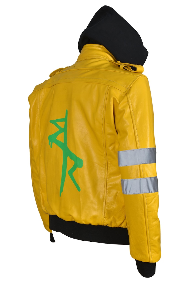 May include: Yellow bomber jacket with a black hood and cuffs. The back features a green graphic design. Reflective silver stripes are on the sleeves. The jacket is made of a smooth, shiny material.