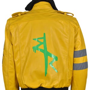 May include: Yellow leather jacket with a black hood and cuffs. The back of the jacket features a green graphic design. The jacket has a bomber style with a ribbed hem and cuffs, and reflective stripes on the sleeves.