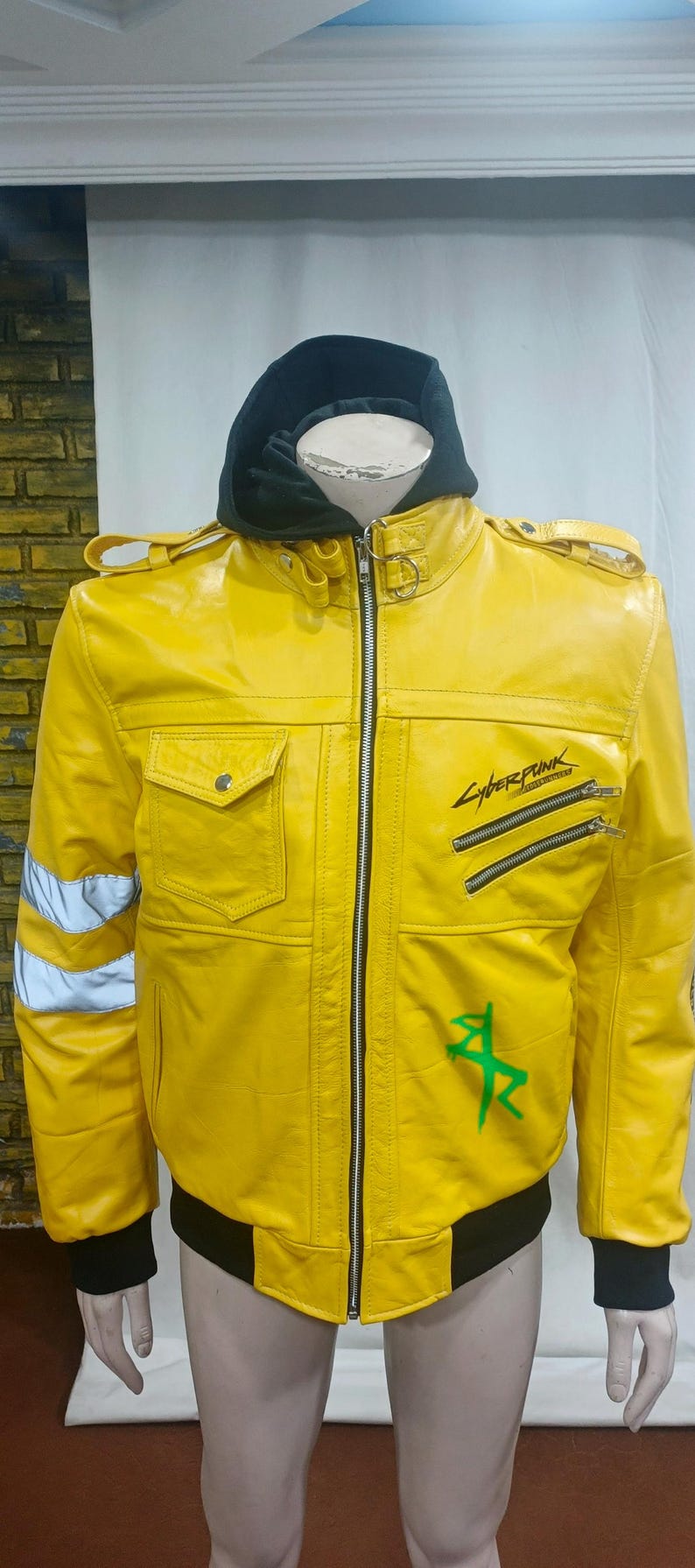 May include: A bright yellow leather jacket with a black hood and cuffs. The jacket features a zipper closure, two front pockets, and the word "Cyberpunk" printed on the front. Reflective stripes are on the sleeves.