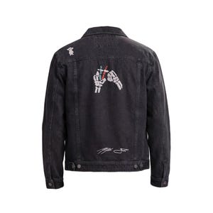 Könnte beinhalten: Eine schwarze Jeansjacke mit einem Rückendesign aus weißen Skeletthänden, die kleine blaue und rote Objekte halten. Ein kleines weißes Kreaturensymbol befindet sich auf der linken Schulter und eine weiße Signatur-Grafik ist am unteren Saum.