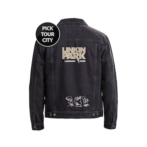 May include: A black denim jacket featuring the text LINKIN PARK LONDON 2026 in beige on the back, with a circular badge stating PICK TOUR CITY and a collection of white printed signatures below the main text, including buttoned cuffs and hem.