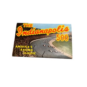May include: Vintage print featuring the Indianapolis 500 race. The image shows race cars on a track with spectators in the background. Text includes "The Indianapolis 500" in red and yellow, and "America's Racing Classic."