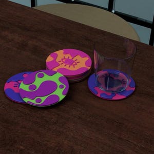 May include: A collection of colorful drink coasters with abstract designs. The coasters feature vibrant patterns in purple, pink, green, and orange. A clear glass sits on a matching coaster, all arranged on a dark wooden surface.