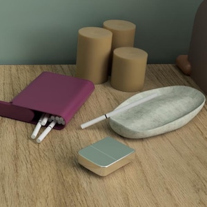 May include: A still life arrangement featuring a plum-colored cigarette case with cigarettes, an ashtray, and a small rectangular container. The items are on a wooden surface, with cylindrical objects and abstract shapes in the background.