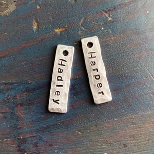 May include: Two silver metal tags with the names "Hadley" and "Harper" engraved on them.