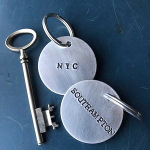 May include: Two silver keyrings with a key. One keyring has the text "NYC" and the other has the text "Southampton".