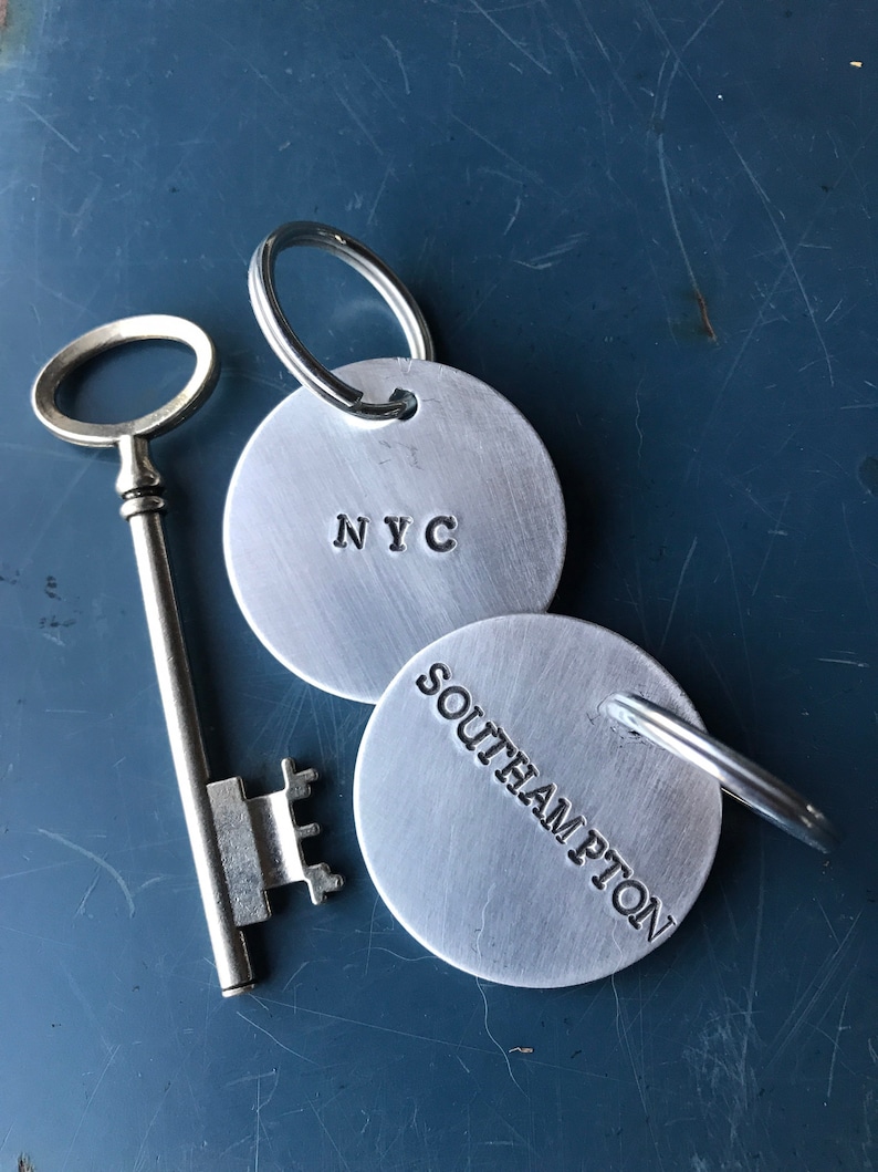 May include: Two silver keyrings with a key. One keyring has the text "NYC" and the other has the text "Southampton".