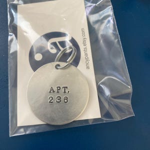 May include: A silver key chain with a round tag that says "APT. 236" in black lettering.