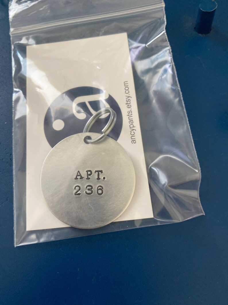 May include: A silver key chain with a round tag that says "APT. 236" in black lettering.