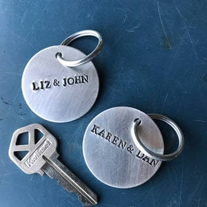 May include: Two silver keyrings with round metal tags. The tags are engraved with the names "Liz & John" and "Karen & Dan".