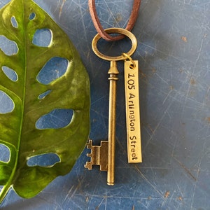 May include: A gold-toned skeleton key with a brown leather cord and a tag that reads "105 Arlington Street".