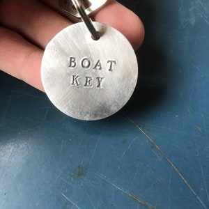 May include: A silver key ring with a round metal tag that says "BOAT KEY" in all caps.