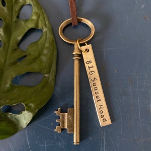 May include: A gold-toned skeleton key with a brown leather cord and a metal tag that reads "816 Sunset Road".