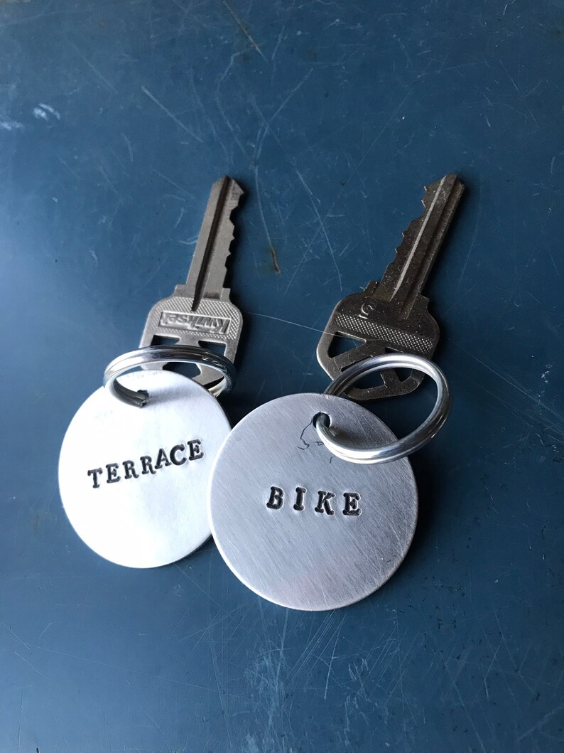 May include: Two silver keyrings with round metal tags. The tag on the left says "TERRACE" and the tag on the right says "BIKE".