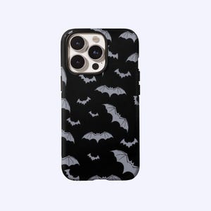 May include: Black phone case with a repeating pattern of gray bats. The case has a black border and a camera cutout. The bats are in various sizes and orientations, creating a spooky, Halloween-themed design. The case is designed for a smartphone.