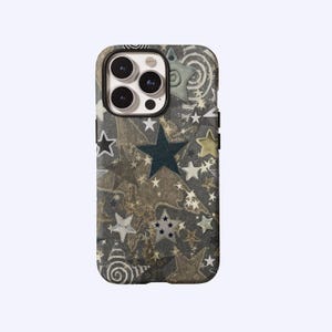 May include: A phone case with a pattern of various stars in shades of gray, gold, and navy blue. The case has a dark gray background with a textured appearance. The stars are of different sizes and styles, creating a celestial design.